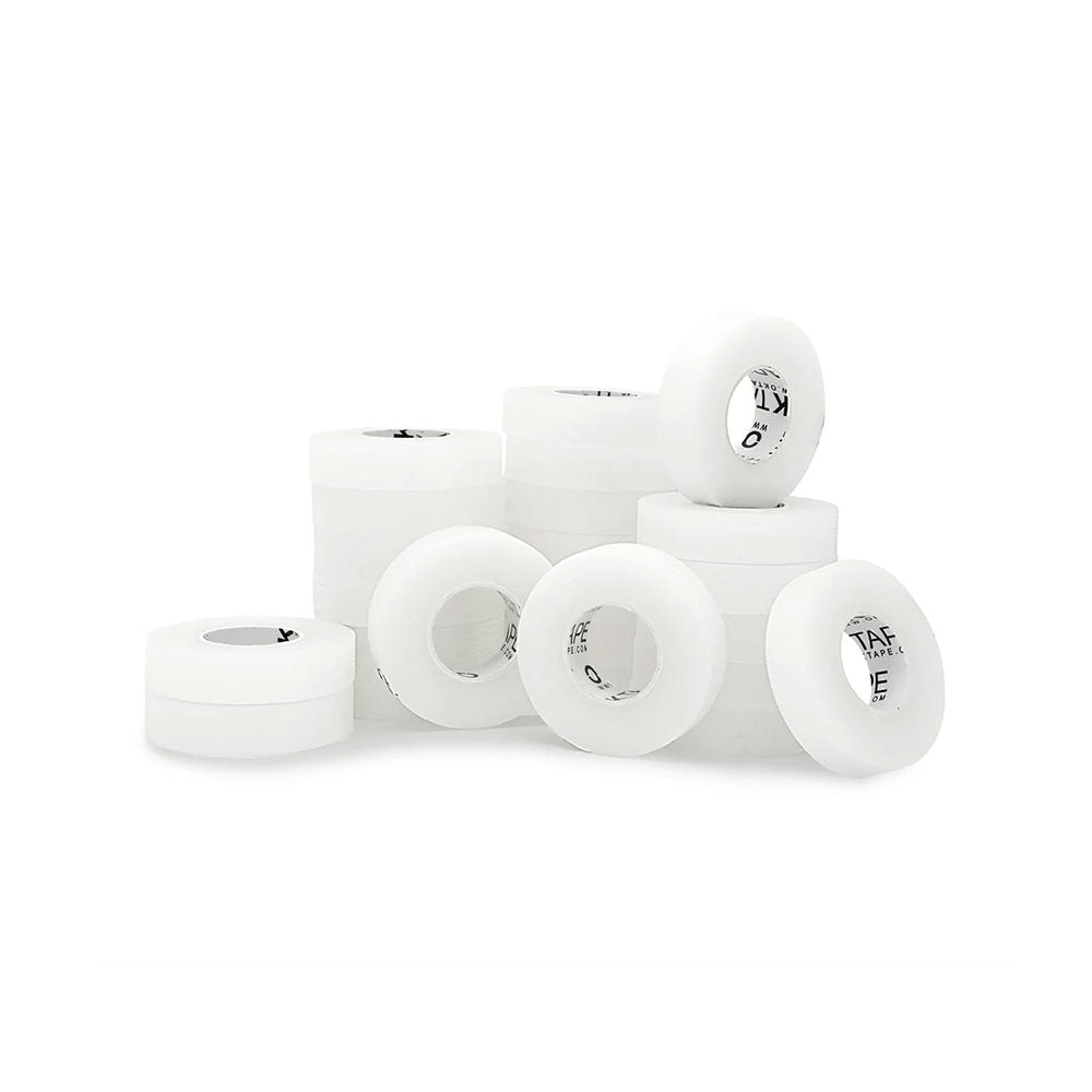White skateboard wheels, evoking the look of large rolls of Transpore Tape by MedPharma USA, are displayed on a white surface. The arrangement features wheels both upright and flat, revealing black text inside.